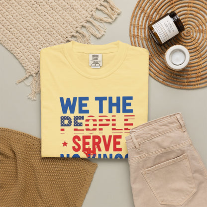 Yellow t-shirt with 'We the People Serve Nothing' text on a neutral surface with accessories.