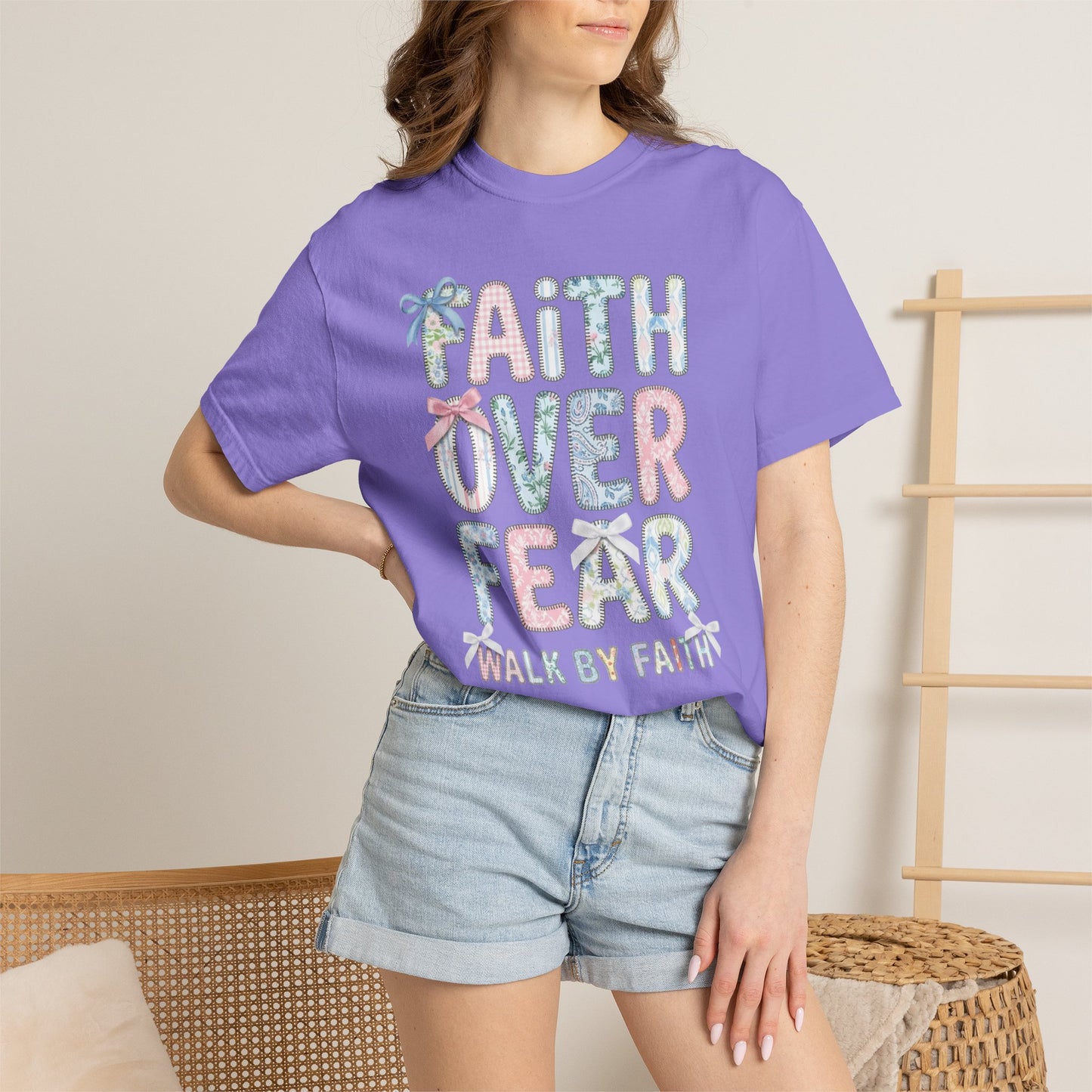Person wearing a violet t-shirt with 'Faith Over Fear' text, standing against a neutral background.