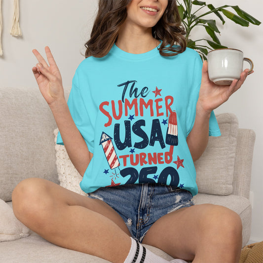 Person wearing a lagoon blue t-shirt with 'The Summer USA Turned Red' text, sitting on a couch holding a mug.