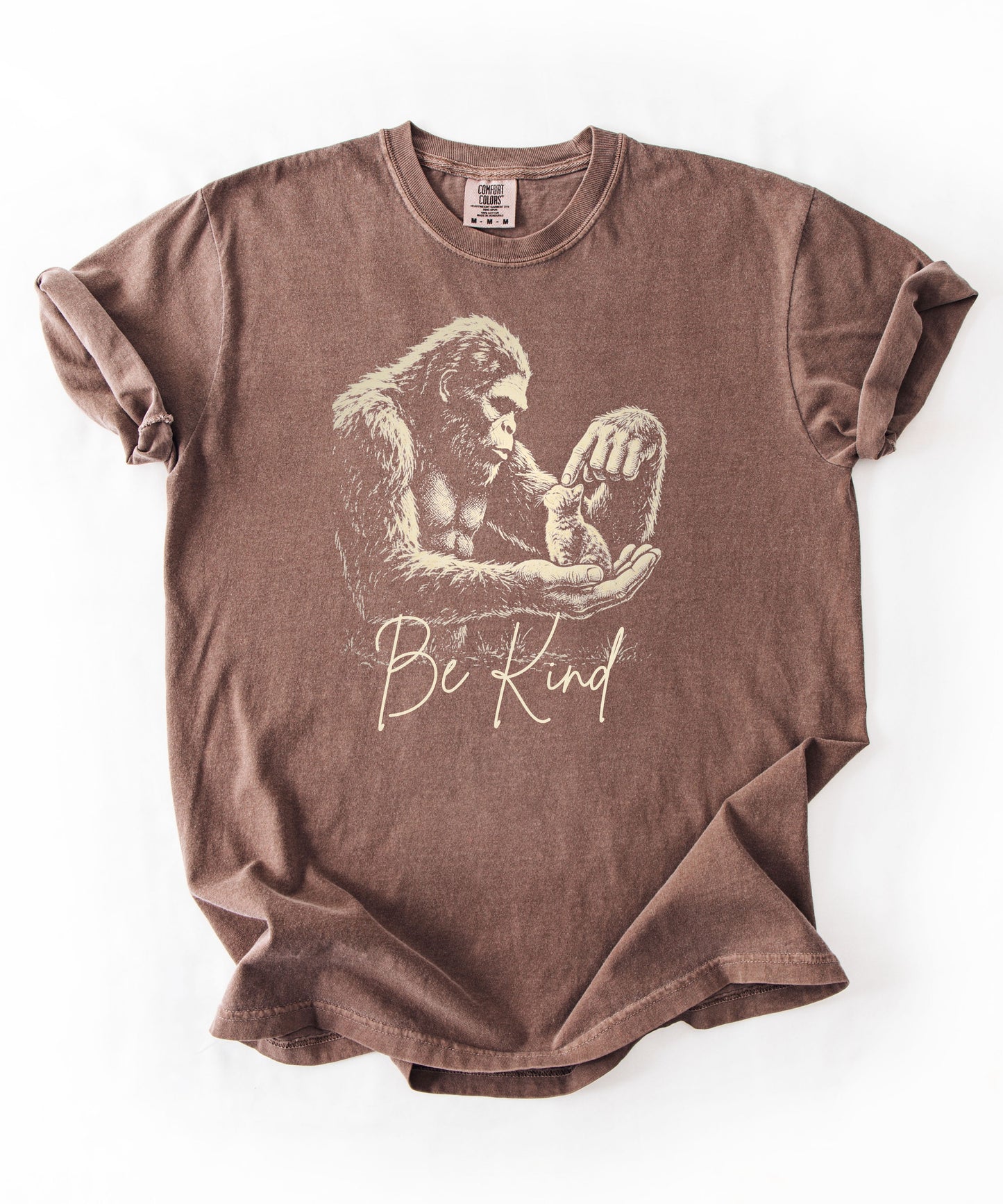 Bigfoot booping a cat on the nose graphic tee in Espresso — "Be Kind" garment-dyed heavyweight shirt