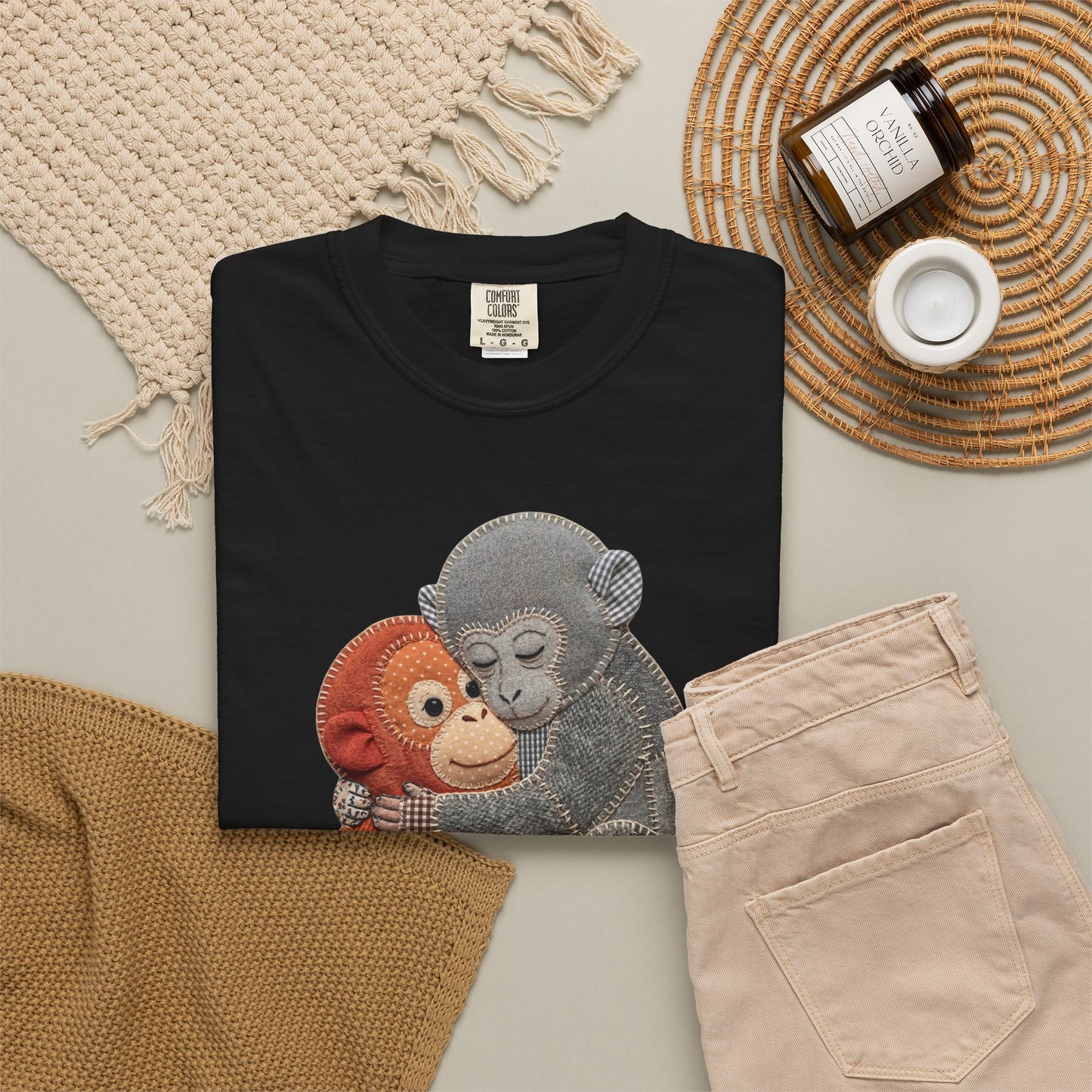 Black sweatshirt with monkey design on a neutral surface with accessories.