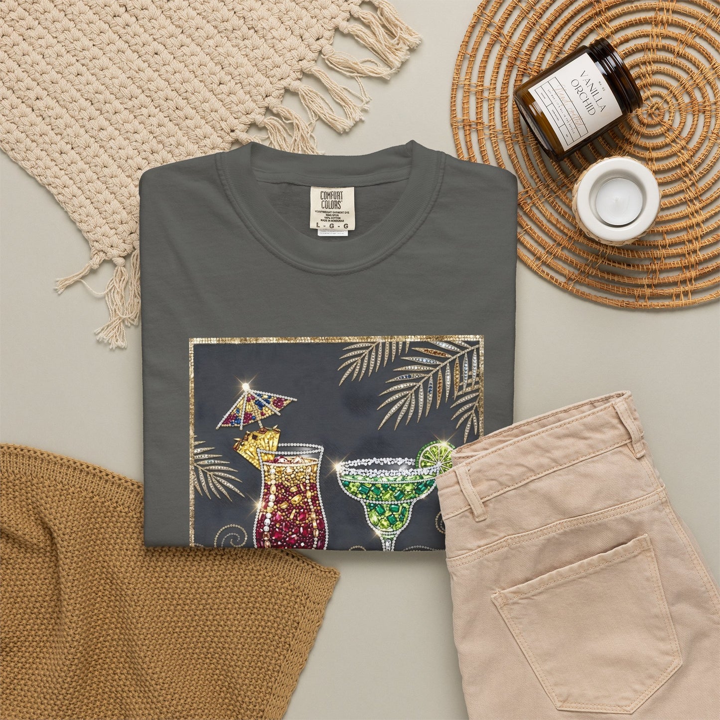 pepper t-shirt with cocktail graphic on a neutral surface with pants and decor items.
