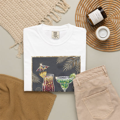White t-shirt with cocktail graphic, beige pants, and decorative items on a neutral background