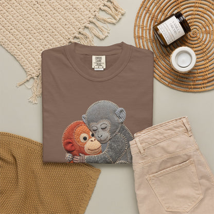 Folded espresso t-shirt with monkey design on a neutral surface with accessories.