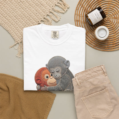 White t-shirt with monkey design on a neutral surface with beige pants and decorative items.
