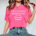 A woman wearing a Crunchberry  pink graphic t-shirt with white text that reads 'IF BEAUTY HAS THE BEAST AND ROMEO HAS JULIET WHAT DO I HAVE? I have work tomorrow', paired with blue jeans against a plain light gray background.