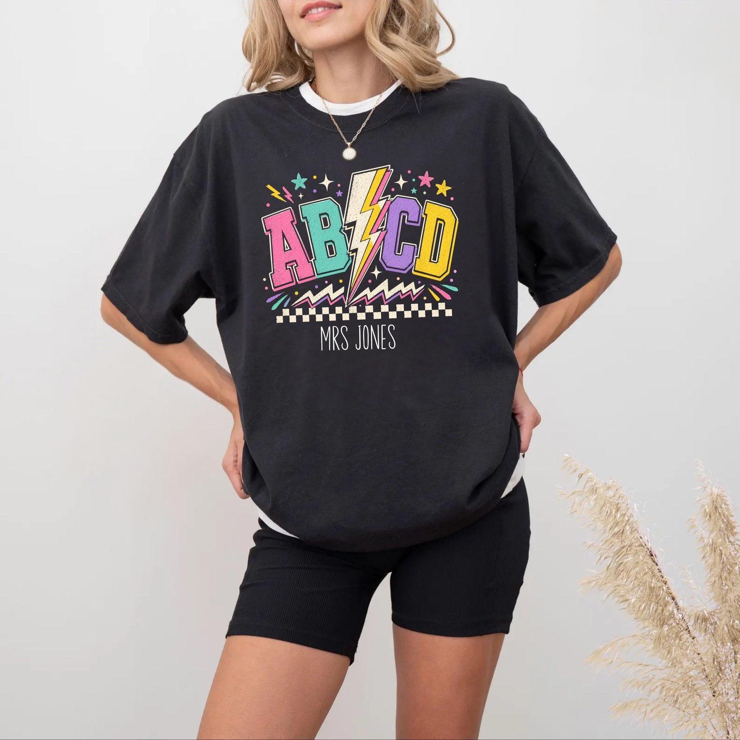 Person wearing a black t-shirt with colorful ABCD graphics on a plain background