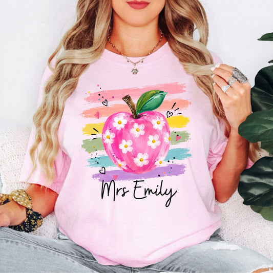 Personalized teacher t-shirt in Blossom with floral apple graphic and colorful brushstroke stripes, custom name in script — garment-dyed cotton tee