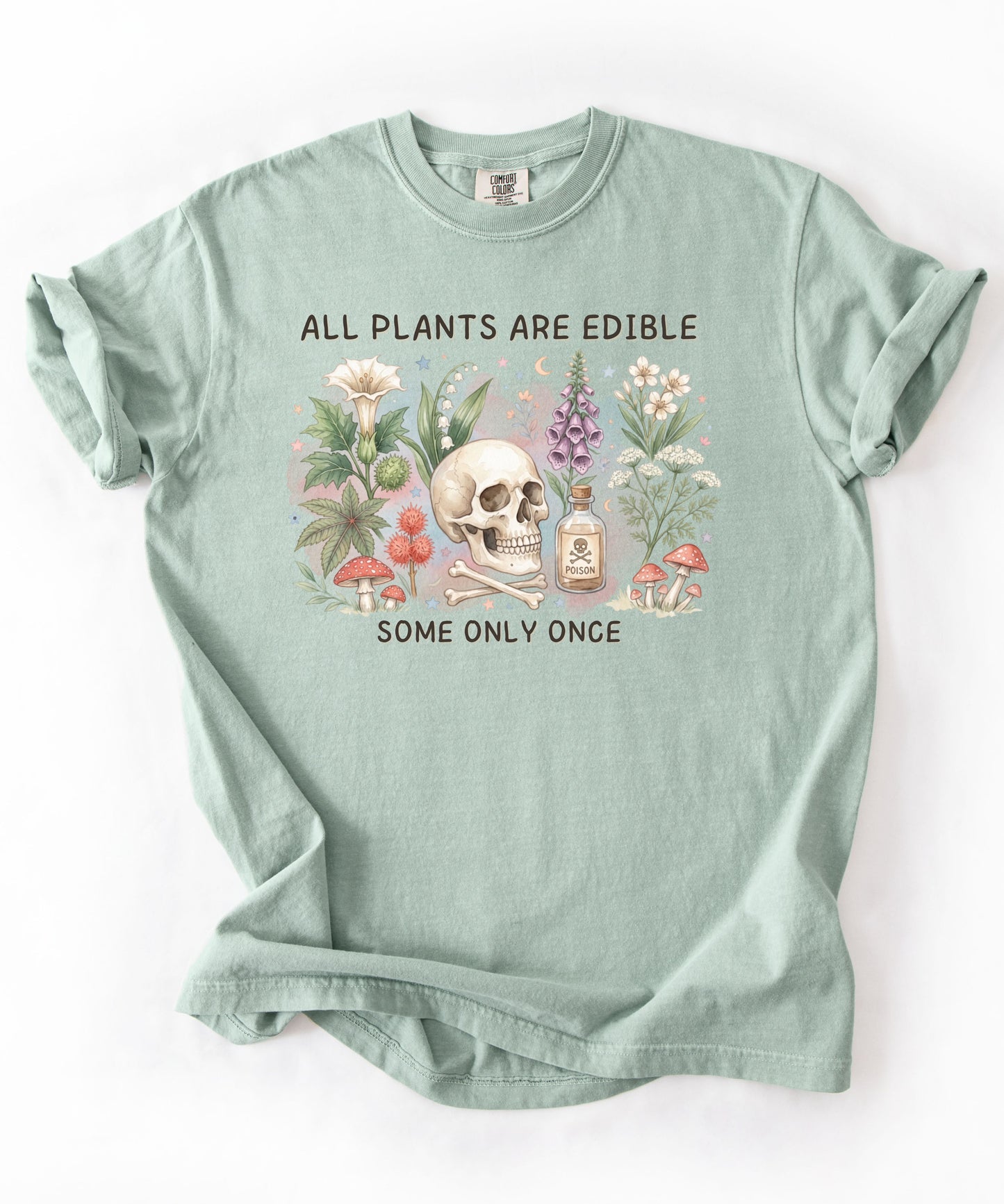 Botanical skull graphic tee featuring herbs, mushrooms, and skull illustration with phrase "All plants are edible, some only once" — front view on garment-dyed cotton Bay Color
