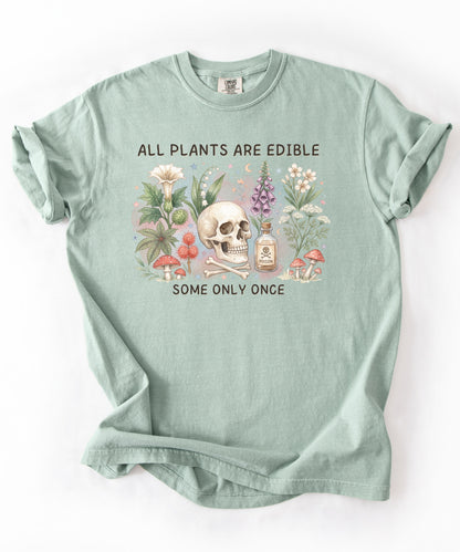 Botanical skull graphic tee featuring herbs, mushrooms, and skull illustration with phrase "All plants are edible, some only once" — front view on garment-dyed cotton Bay Color