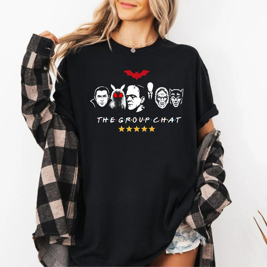 Black garment-dyed unisex t-shirt featuring The Group Chat horror monster squad graphic — Dracula, Mothman with red eyes, Frankenstein, Slender Man, Bigfoot, and Werewolf faces with red bat above and five gold stars below